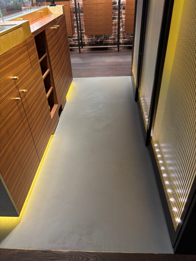 Naadloze beton ciré vloer langs balie met indirecte verlichting