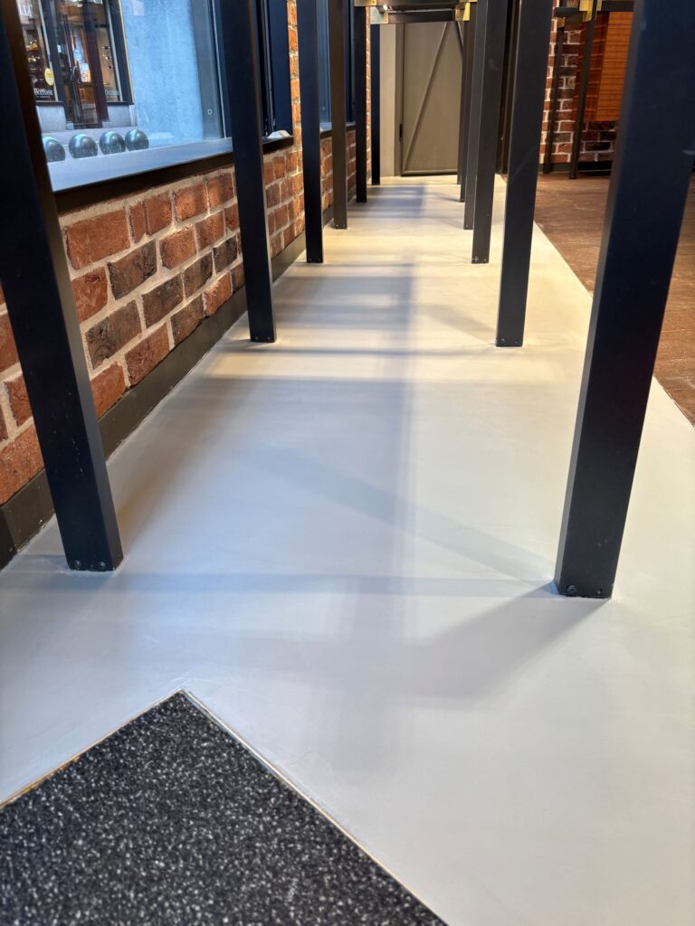 Detail beton ciré vloer onder stalen constructie in luxe winkelinterieur