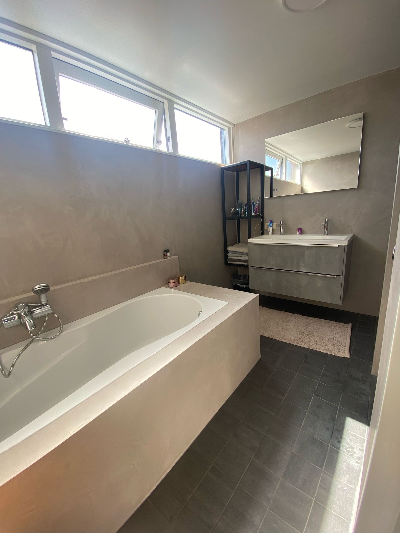 Luxe beton ciré badkamer met ligbad en rustige, naadloze wandafwerking – Stukadoorsbedrijf Ceulemans